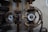 Rusty metal valves with circular handles are positioned against a textured wall. The valves show signs of wear and aging, with visible rust and corroded surfaces.