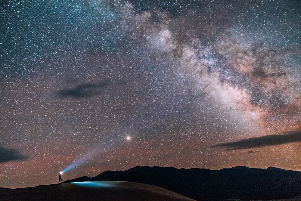 Person mit Taschenlampe unter grauem Himmel mit Sternen