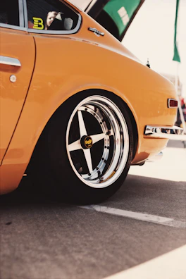 Vintage car gleaming under natural sunlight at an outdoor event.