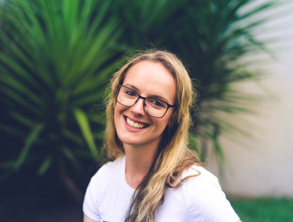 woman wearing white crew-neck shirt near green leaf plant