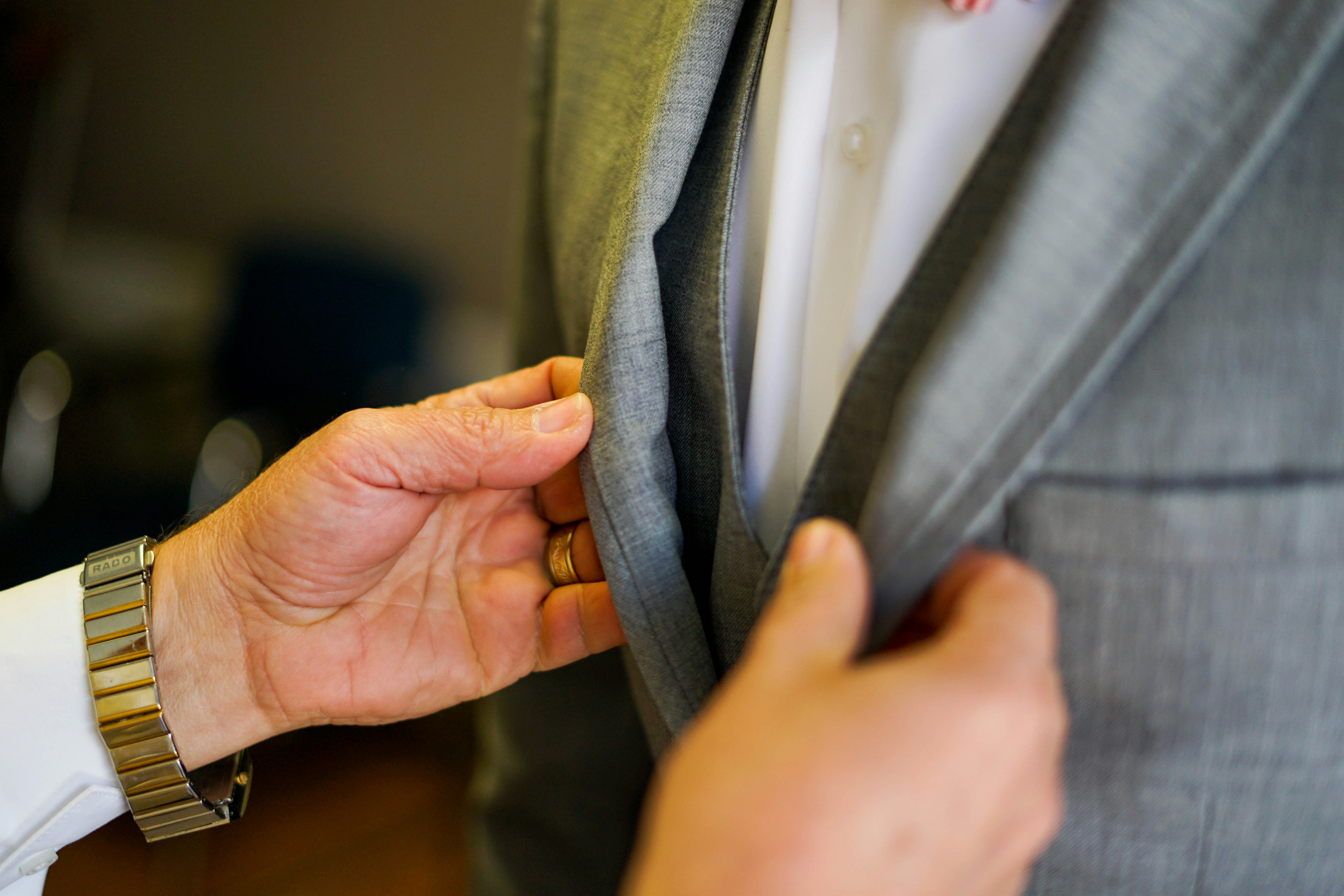 person holding person wearing gray suit jacket