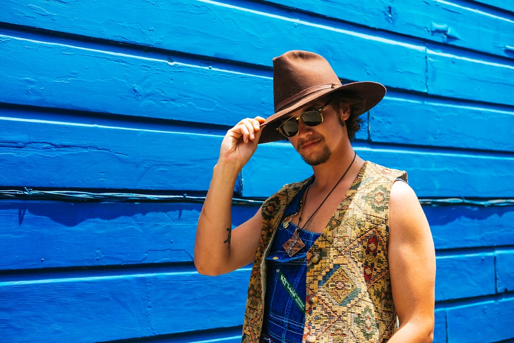 man wearing brown cowboy hat standing on front of blue wall