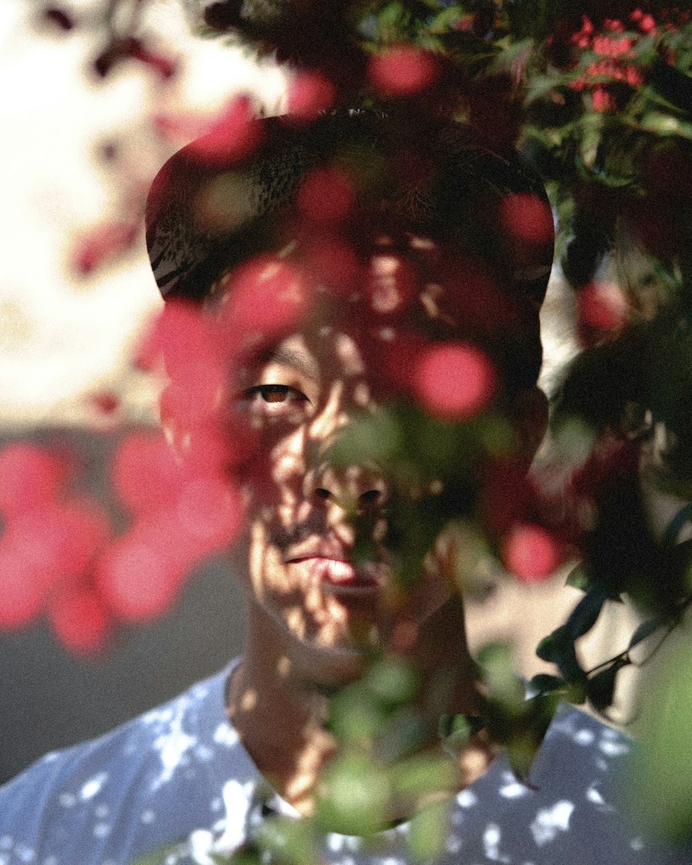 Mann in weißem Hemd mit Rundhalsausschnitt posiert in der Nähe von Blumen