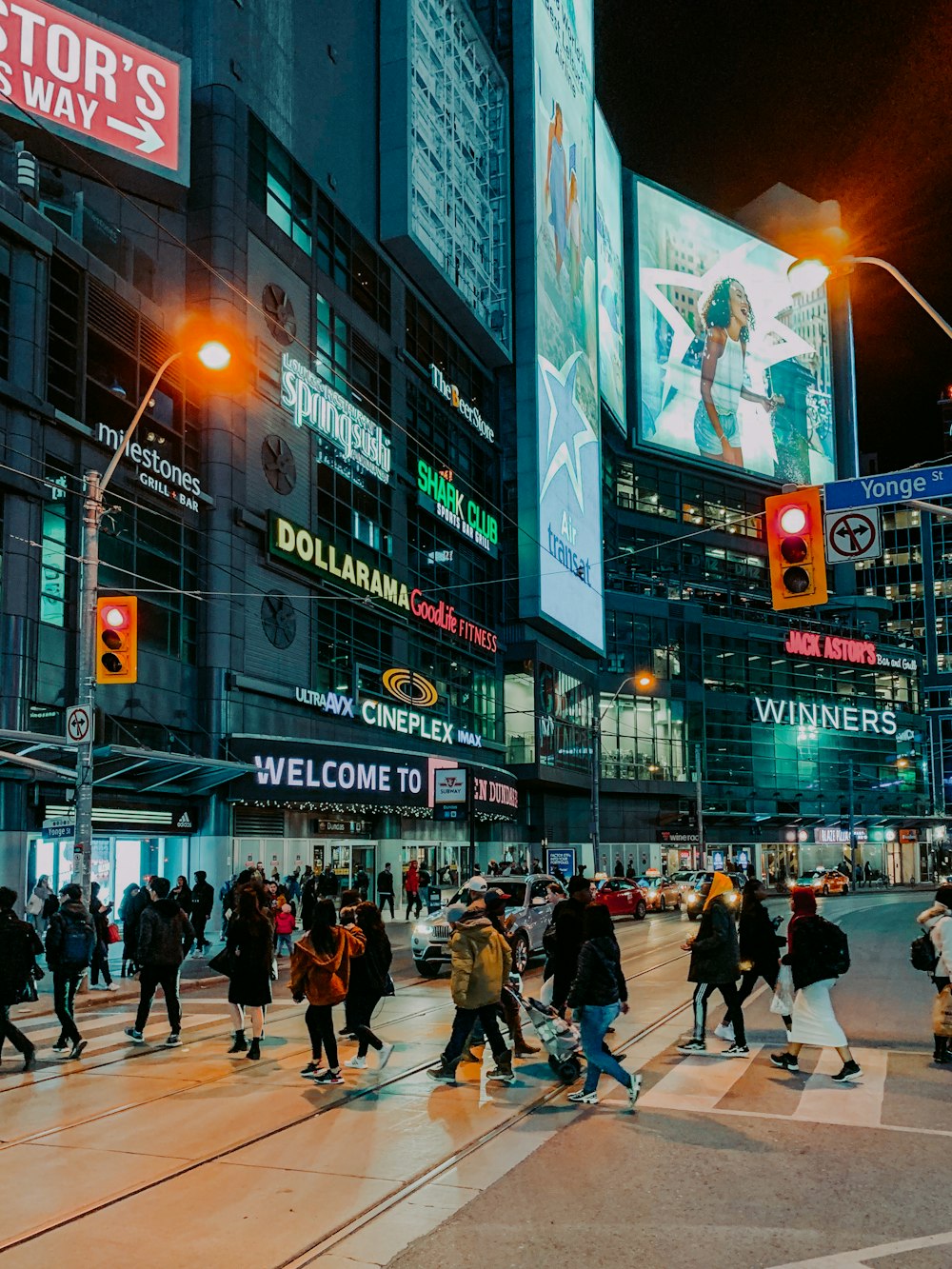 people walking and passing on pedestrian lane near high-rise buildings and different vehicles on road during night time