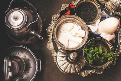 Elegant Moroccan tea service set on a carved wooden tray with mint leaves.