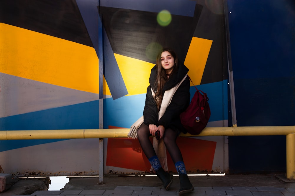 woman sitting on yellow fence