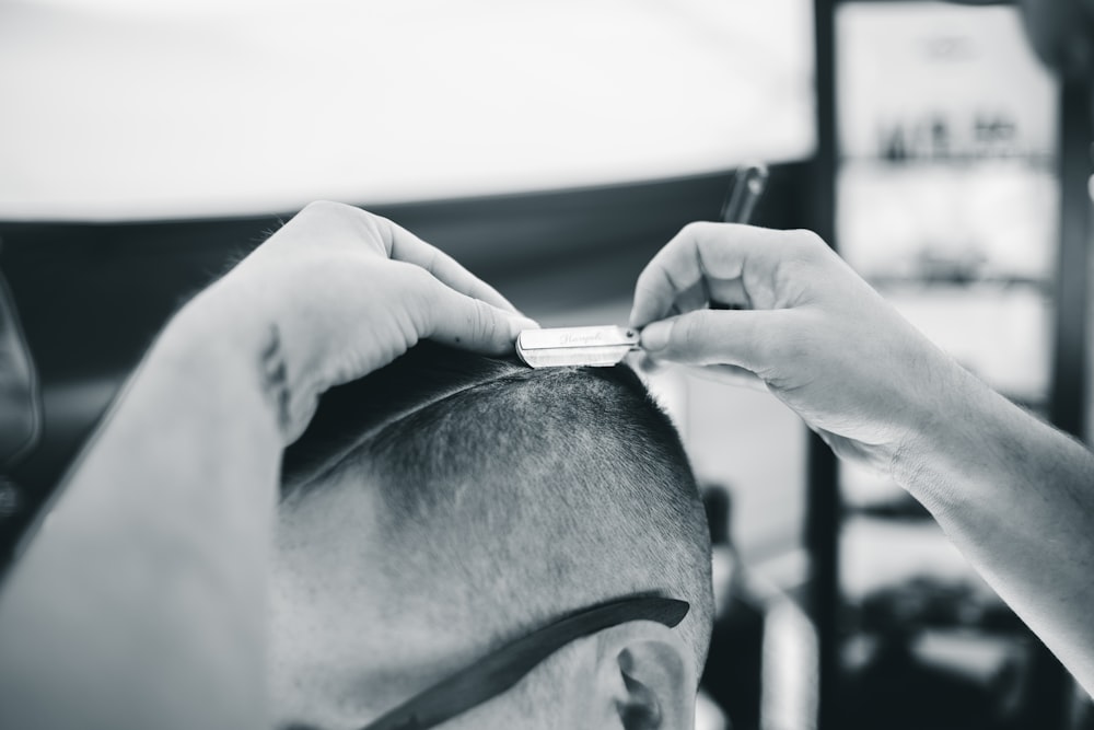 Ein Mann, der einem anderen Mann mit einem Rasiermesser die Haare schneidet