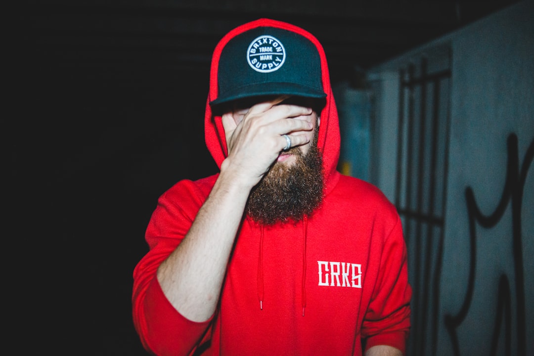 man wearing red hoodie while covering his face