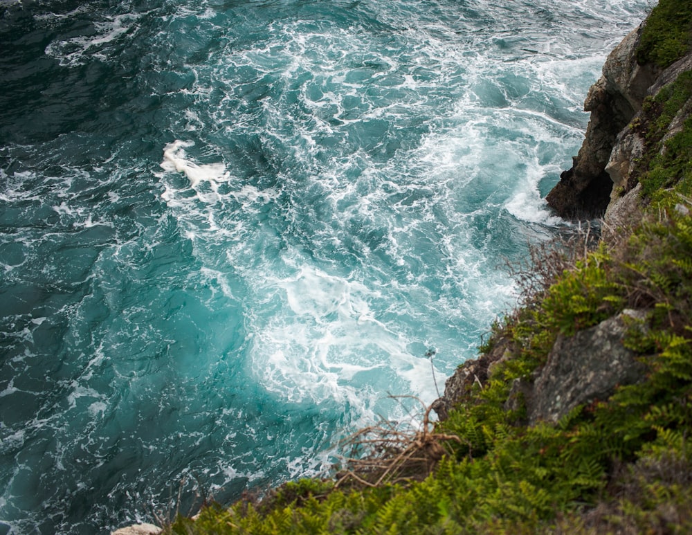 brown and green rock formation beside sea at daytime