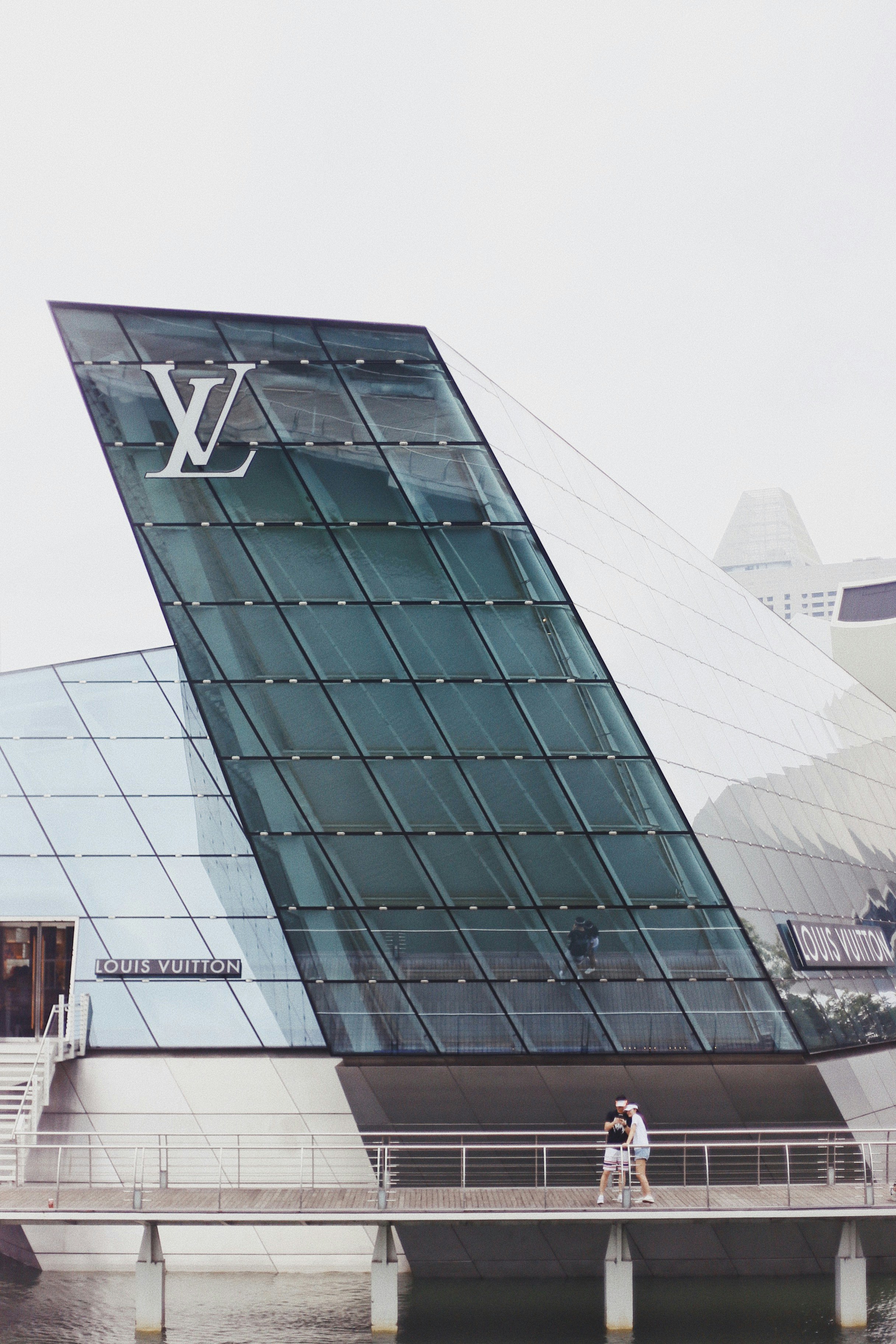 two person standing on bridge near the Louis Vuitton building outdoor during daytime