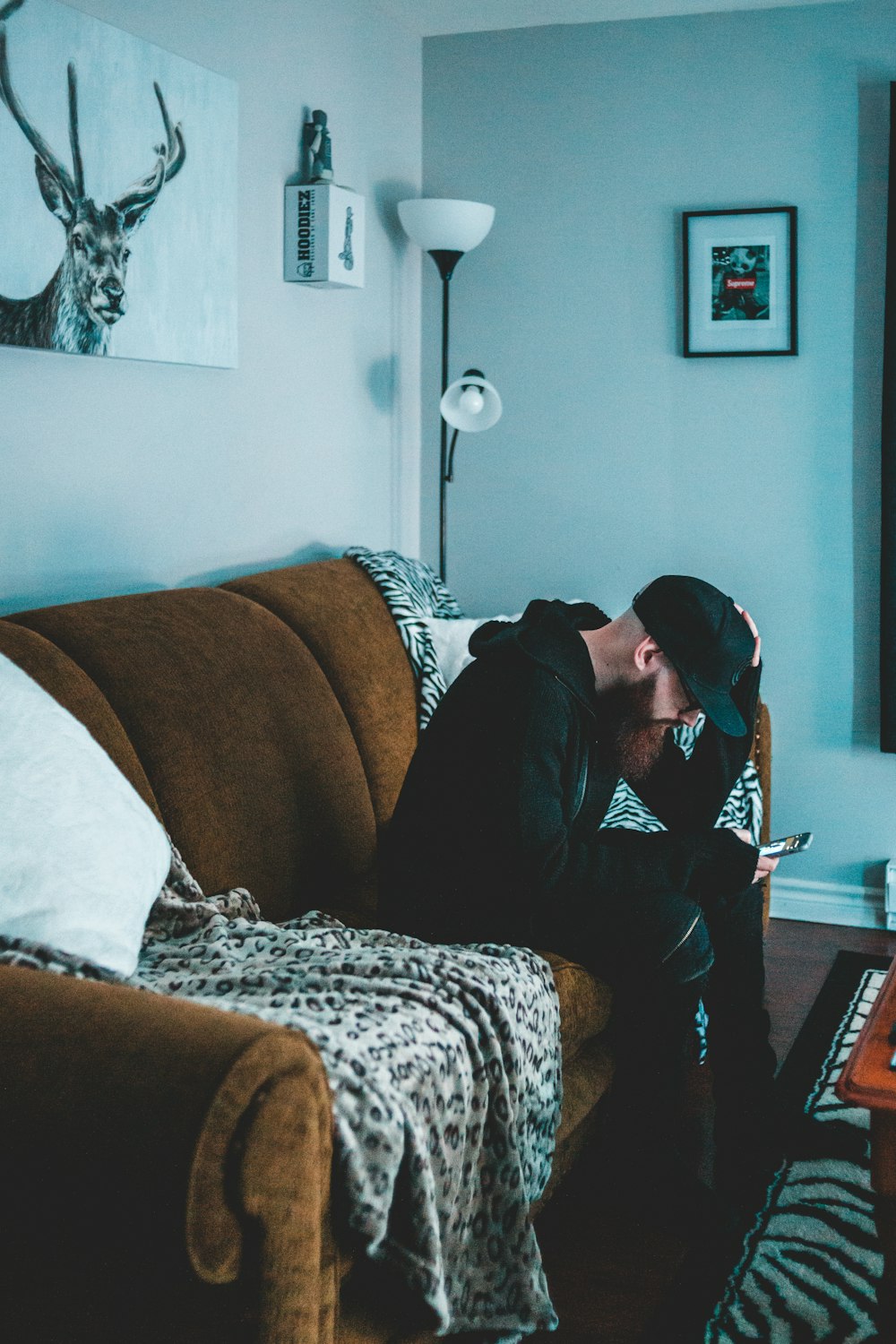 man wearing black hoodie on brown sofa