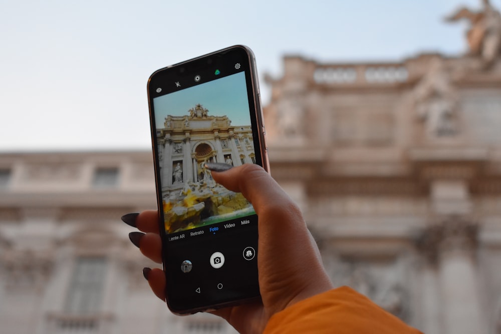 persona che scatta foto di un edificio in cemento marrone