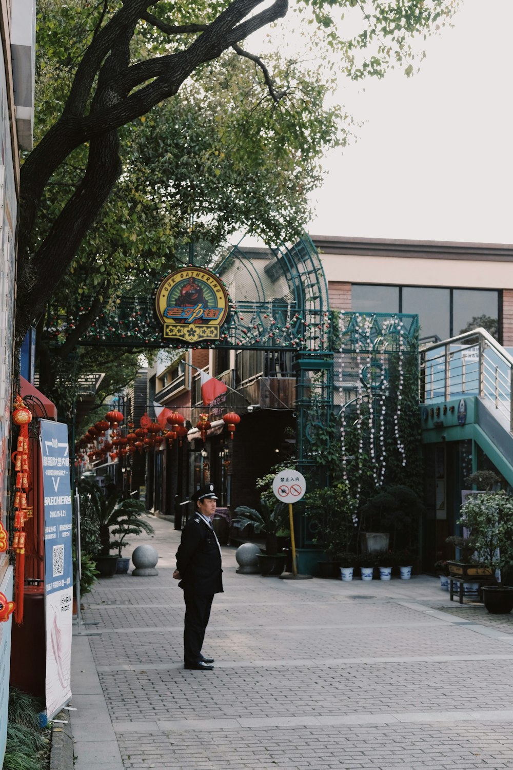 man in black uniform standing under the tree near entrance