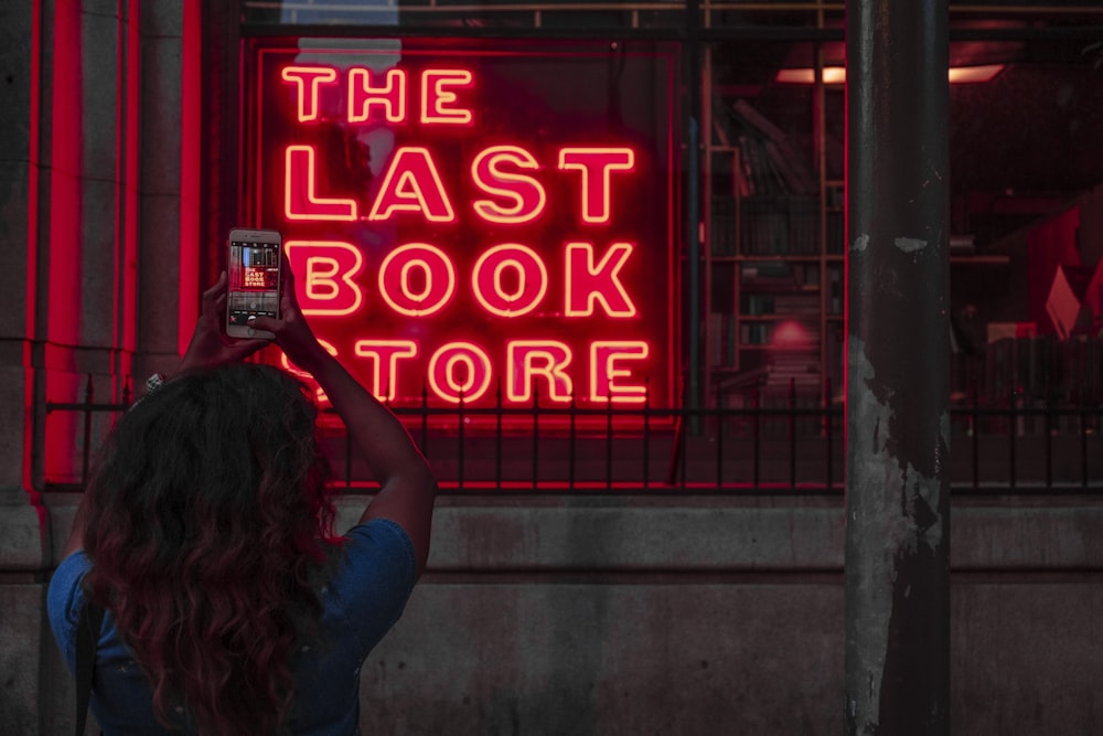 woman taking picture of neon signage