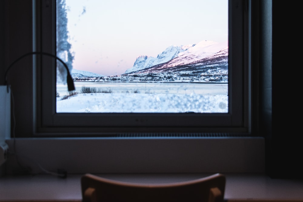 closed white wooden window overlooking snow-covered mountains