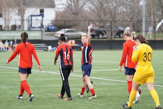 A group of students wearing colorful sports school uniforms playing soccer outdoors.