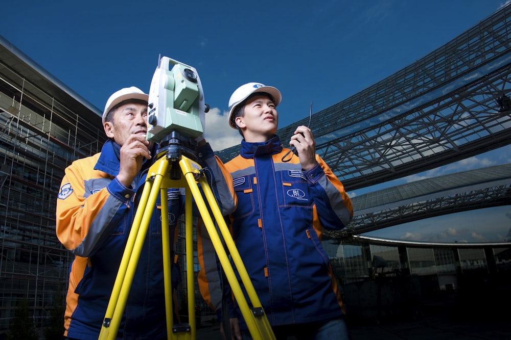 2 men in white hard hat holding a machine