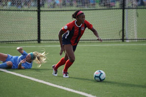 woman in red jersey kicking the ball