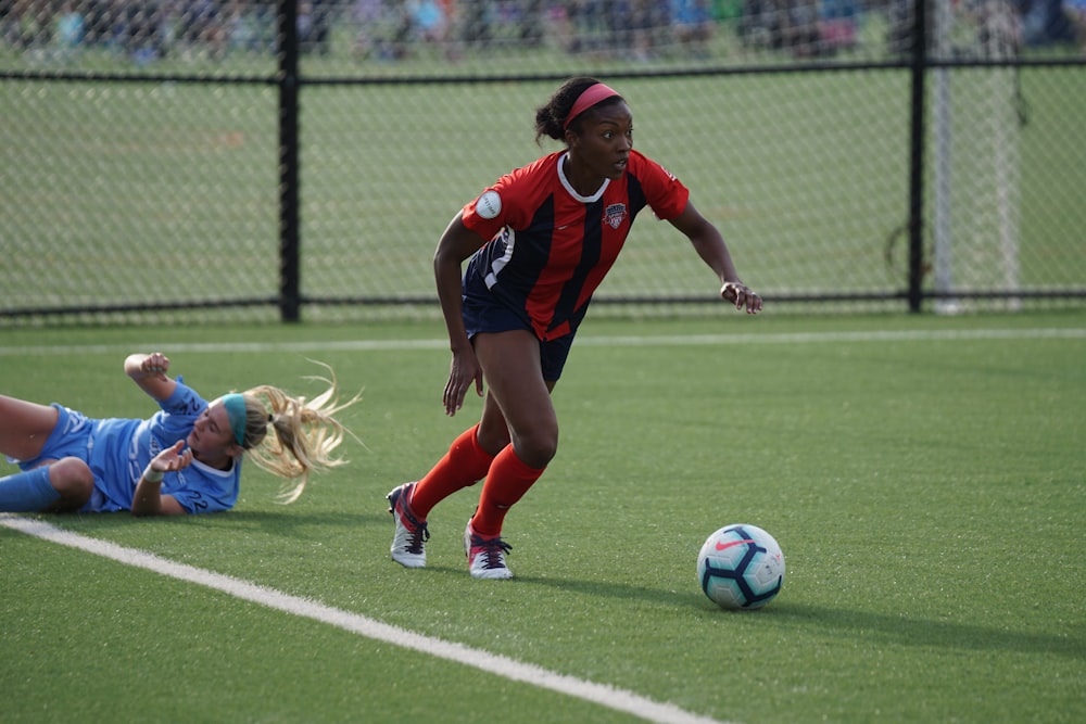 woman in red jersey kicking the ball