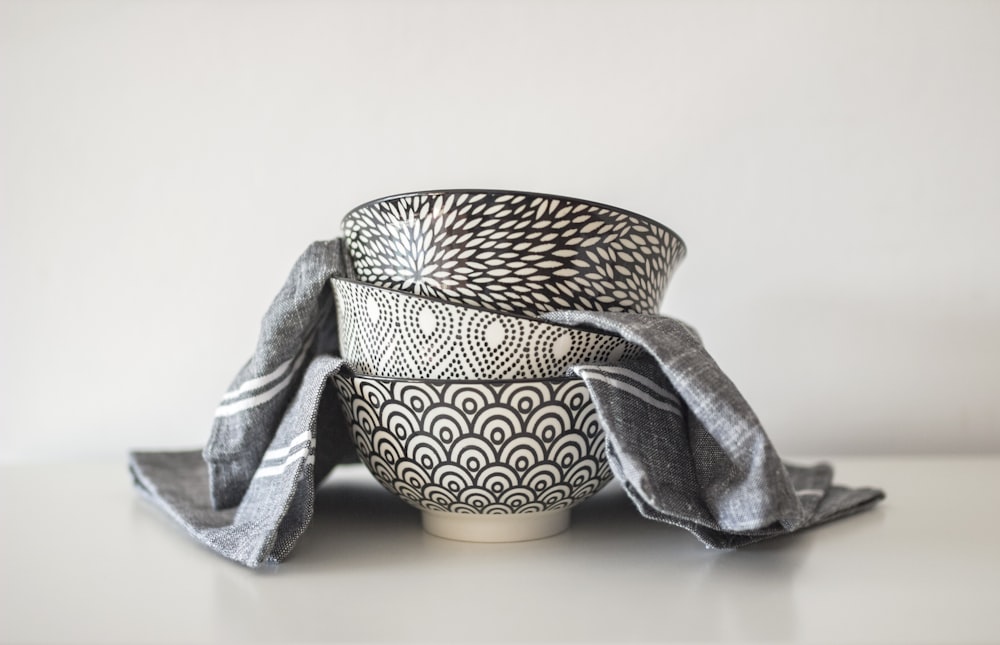 Tre ciotole rotonde in ceramica bianche e nere e tessuto grigio