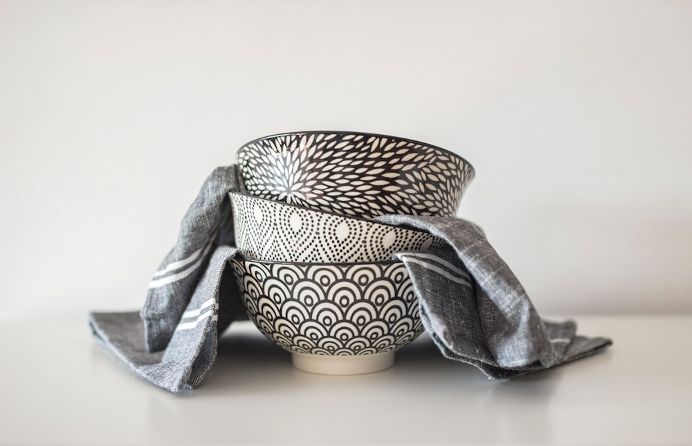 three black and white round ceramic bowls and grey textile