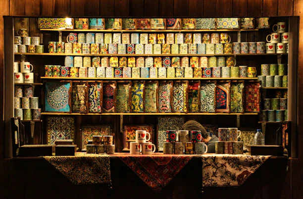Close-up of vibrant handmade ceramic mugs with unique glaze patterns displayed on a rustic wooden shelf