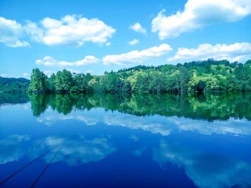 A serene landscape with a calm lake reflecting the sky.