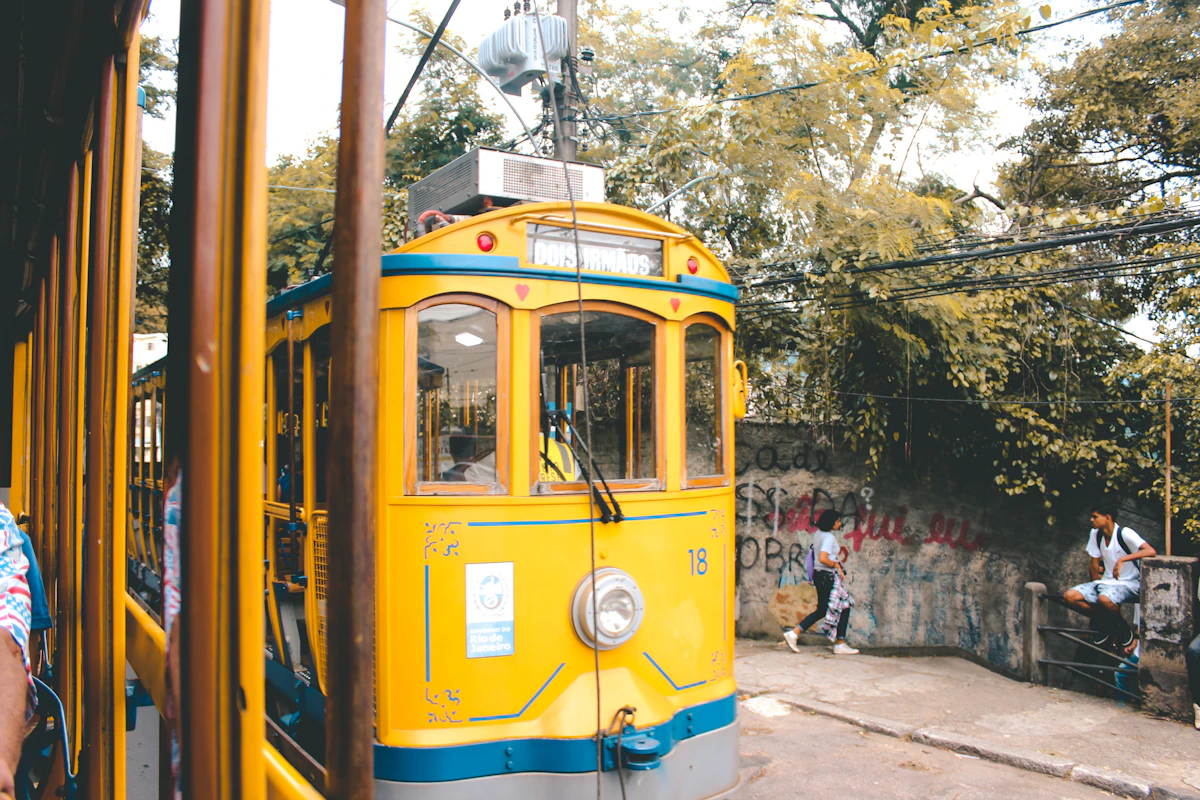 People beside the yellow Santa Teresa tram on a Rio de Janeiro street
