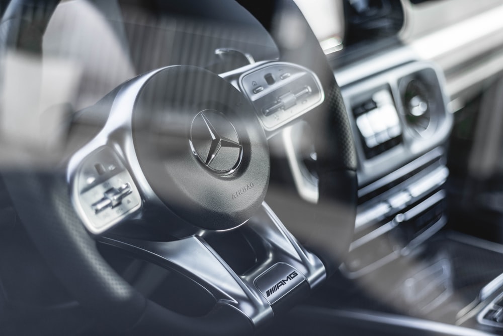 black and grey Mercedez-Benz steering wheel beside black vehicle stereo
