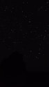 the night sky with stars above a mountain