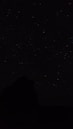 the night sky with stars above a mountain