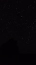 the night sky with stars above a mountain