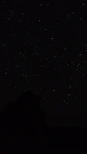 the night sky with stars above a mountain