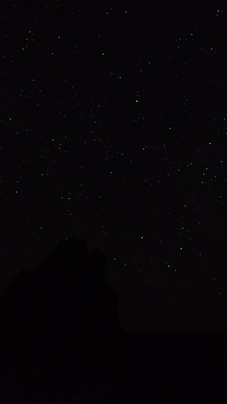 the night sky with stars above a mountain