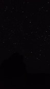 the night sky with stars above a mountain