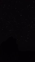 the night sky with stars above a mountain