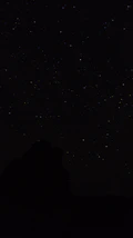 the night sky with stars above a mountain