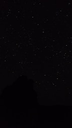 the night sky with stars above a mountain