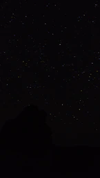 the night sky with stars above a mountain