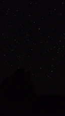 the night sky with stars above a mountain