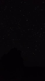 the night sky with stars above a mountain