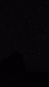 the night sky with stars above a mountain