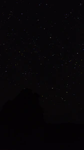 the night sky with stars above a mountain