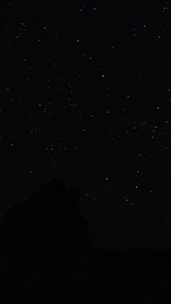 the night sky with stars above a mountain