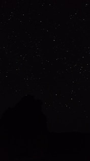 the night sky with stars above a mountain