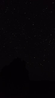 the night sky with stars above a mountain