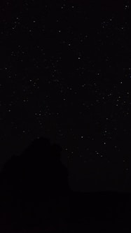 the night sky with stars above a mountain