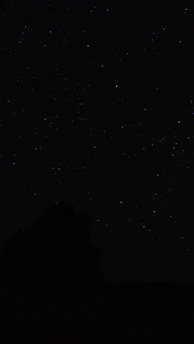 the night sky with stars above a mountain