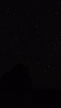 the night sky with stars above a mountain