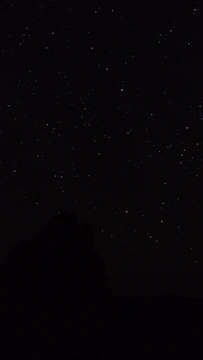 the night sky with stars above a mountain